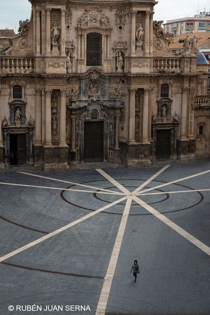Una mujer atraviesa la solitaria plaza del Cardenal Belluga en pleno confinamiento, fotografía de Rubén Juan Serna