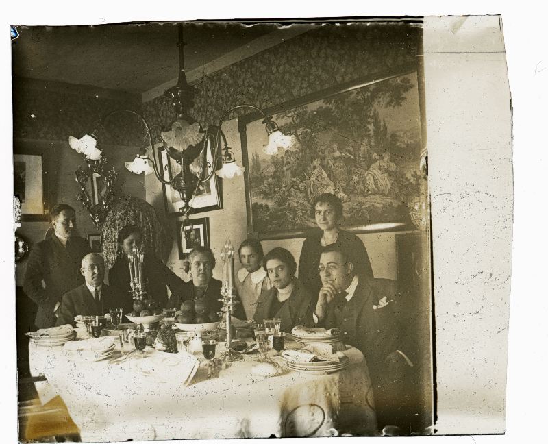 Retrato de grupo familiar sentado ante una mesa engalanada