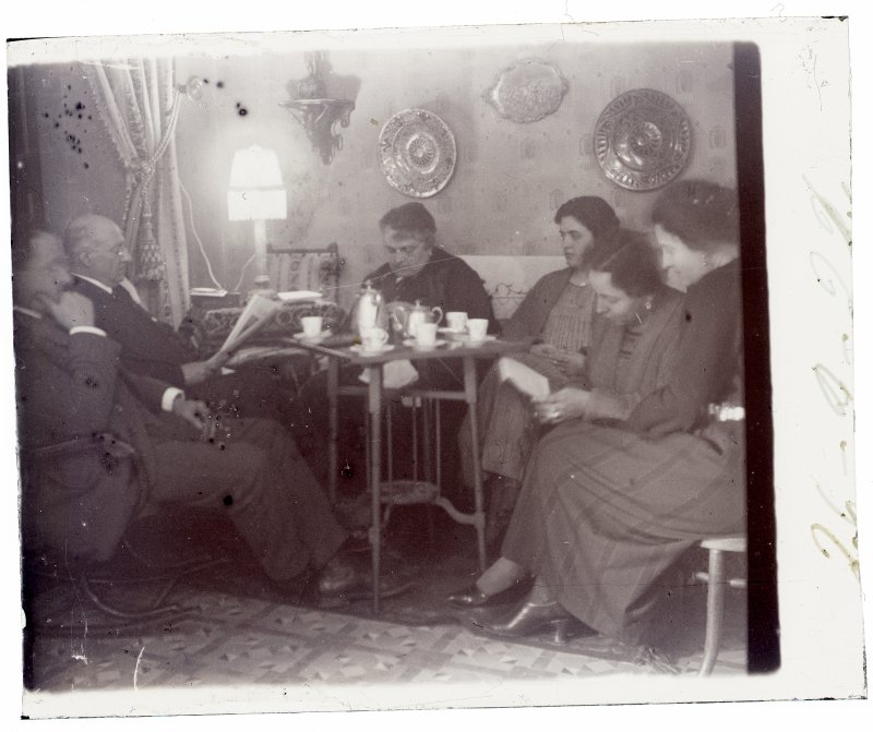 Grupo familiar tomando el té en el salón de una casa burguesa