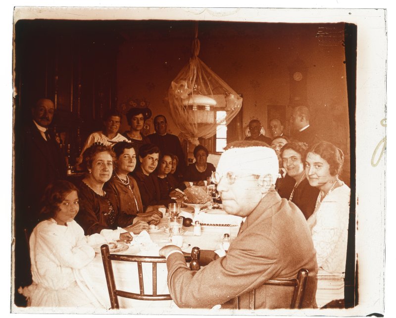 Grupo familiar alrededor de una mesa en el salón o comedor de una casa burguesa