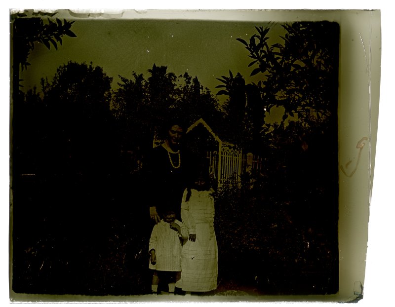 Retrato de una mujer con un niño y una niña vestidos de blanco en el jardín de una casa de la huerta