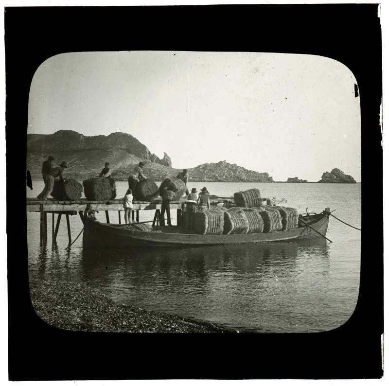 Hombres cargando esparto en un falucho en una playa de la bahía de Levante de Águilas.