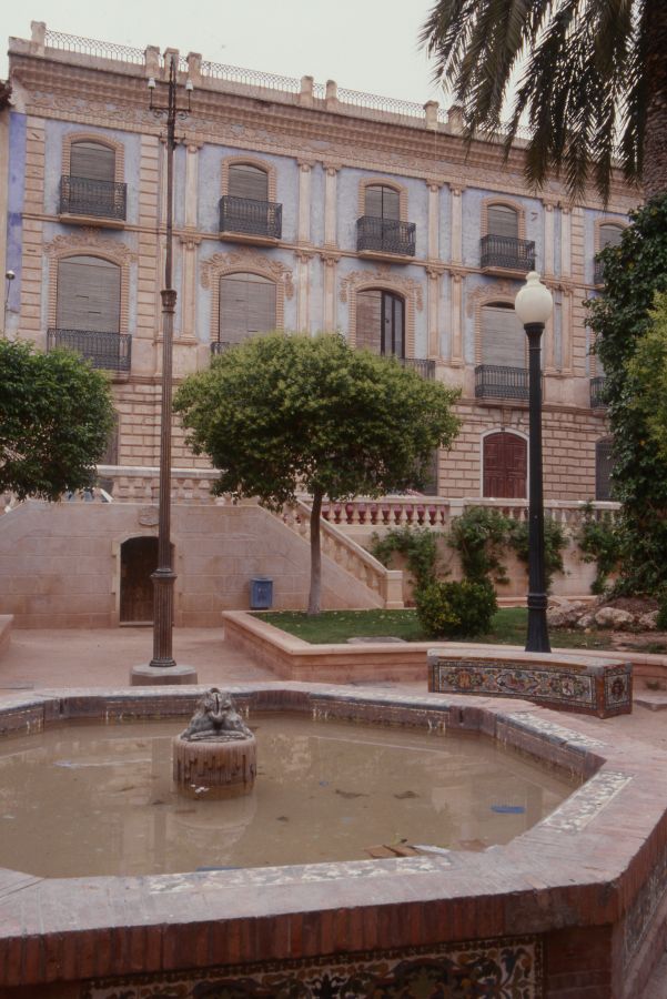 Fuente con edificio histórico al fondo en el Jardín de las Ranas de Jumilla