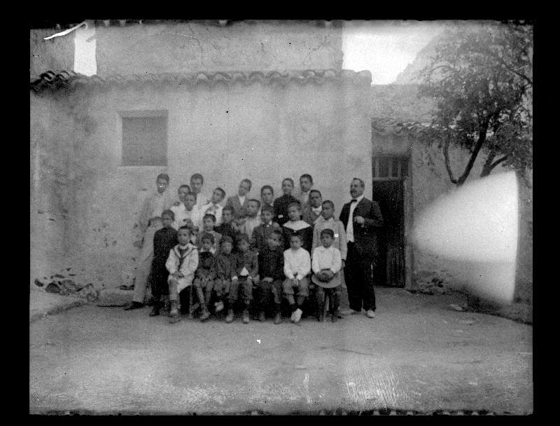 Retrato del maestro Juan Selvas con un grupo de alumnos en el patio de su colegio en la calle Albaicín de Cieza.