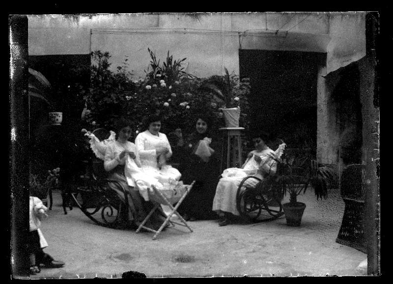 Retrato de cuatro mujeres tejiendo en un patio