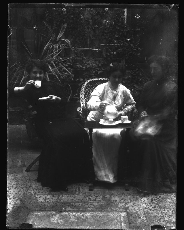 Retrato de tres mujeres tomando té sentadas en un patio