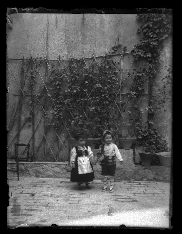 Retrato de dos niños pequeños ataviados de huertanos en un patio