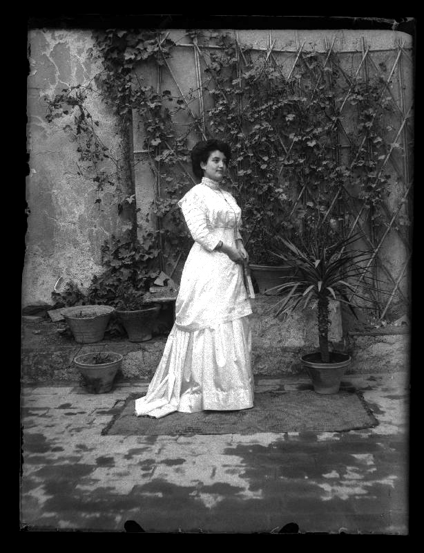 Retrato de cuerpo entero de Antonia Marín González vestida de blanco en un patio.