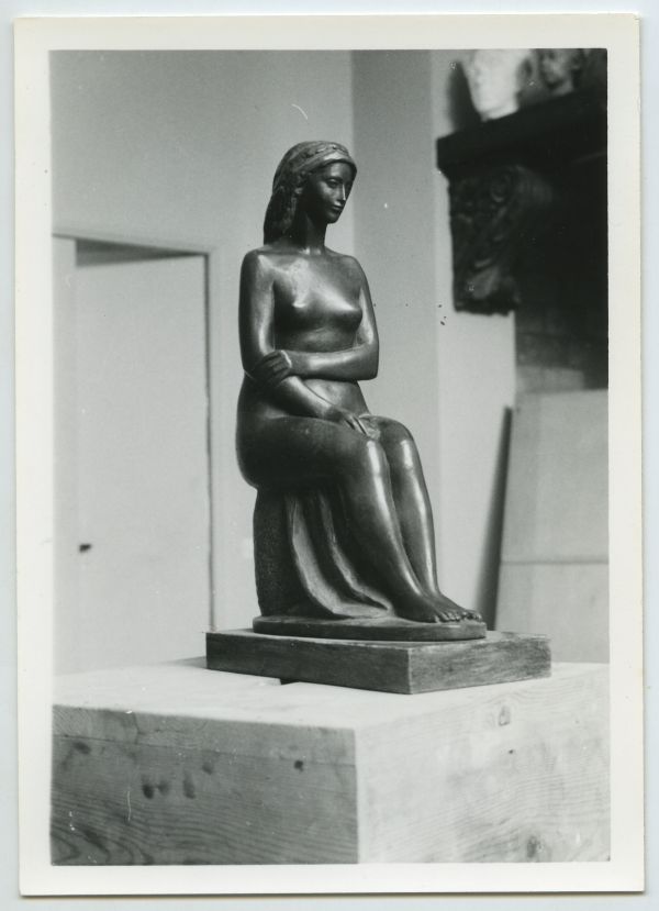 Escultura en bronce de mujer sedente con la mano en un brazo, obra de Juan González Moreno.