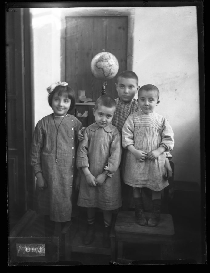Retrato de los hijos de Daniel Jiménez de Cisneros, con bata escolar, posando en el interior de una vivienda