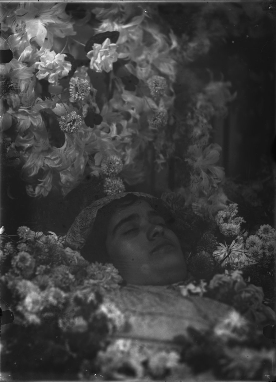 Retrato post mortem de una mujer joven en el interior de su ataúd decorado con flores