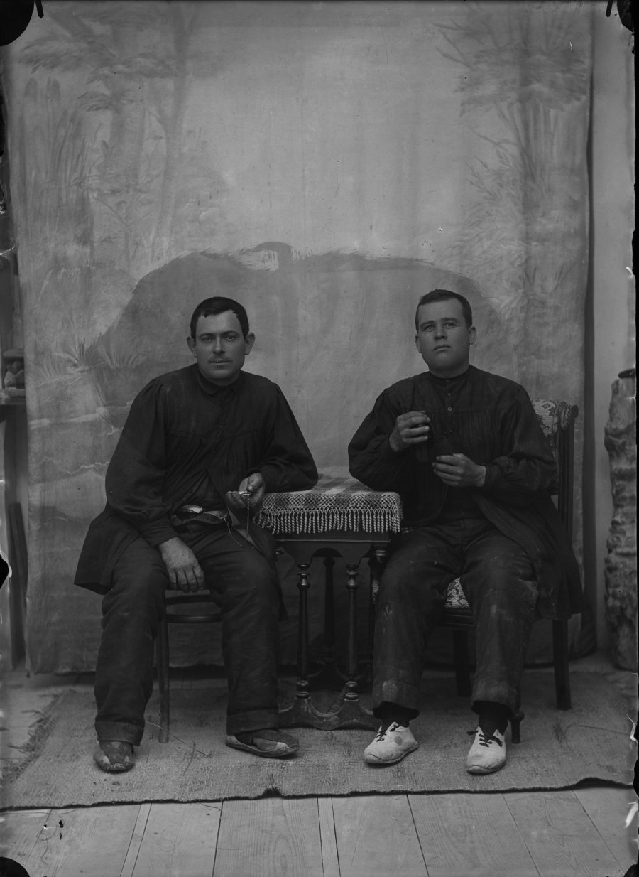 Retrato de estudio de dos hombres jóvenes sentados a una mesa