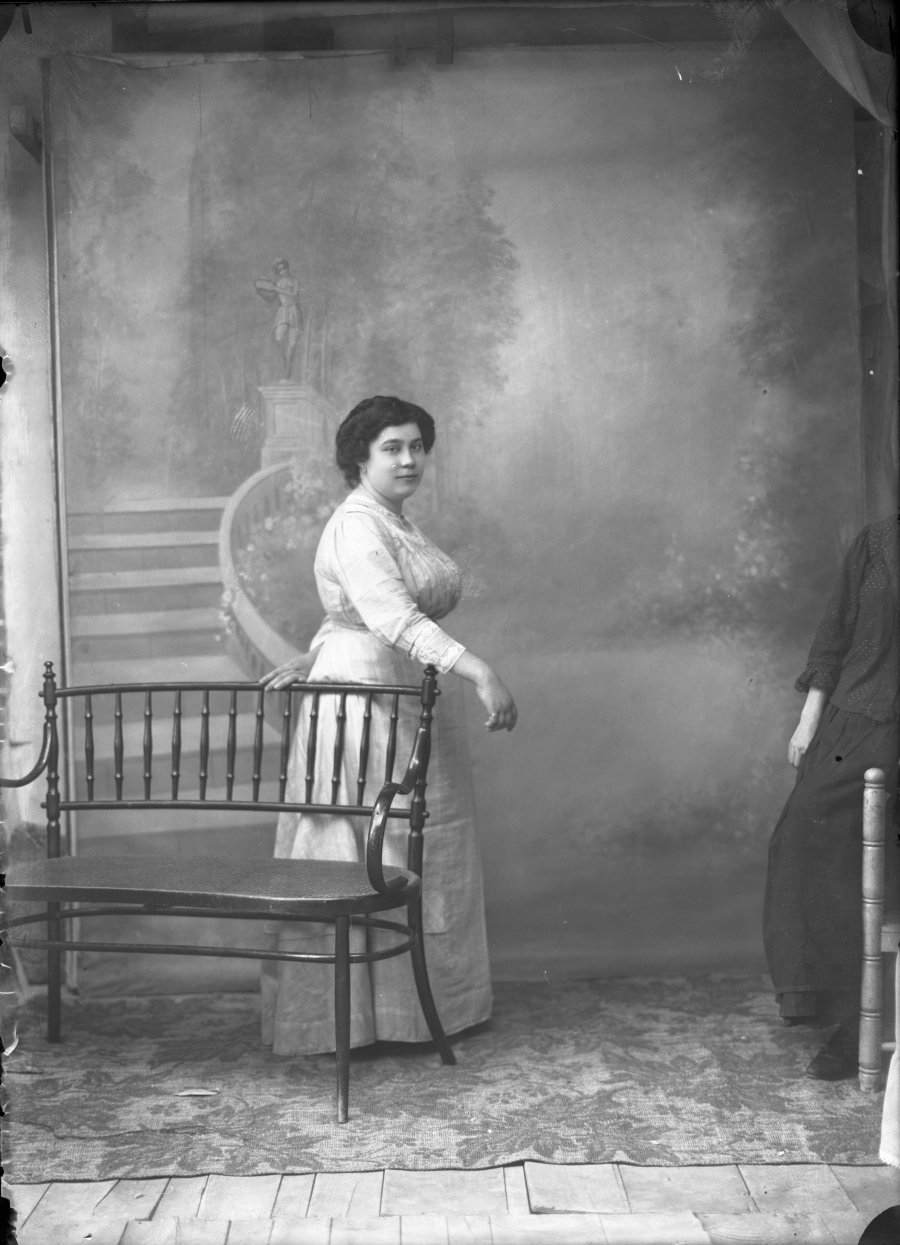 Retrato de estudio de una mujer joven vestida de blanco junto a un banco de madera
