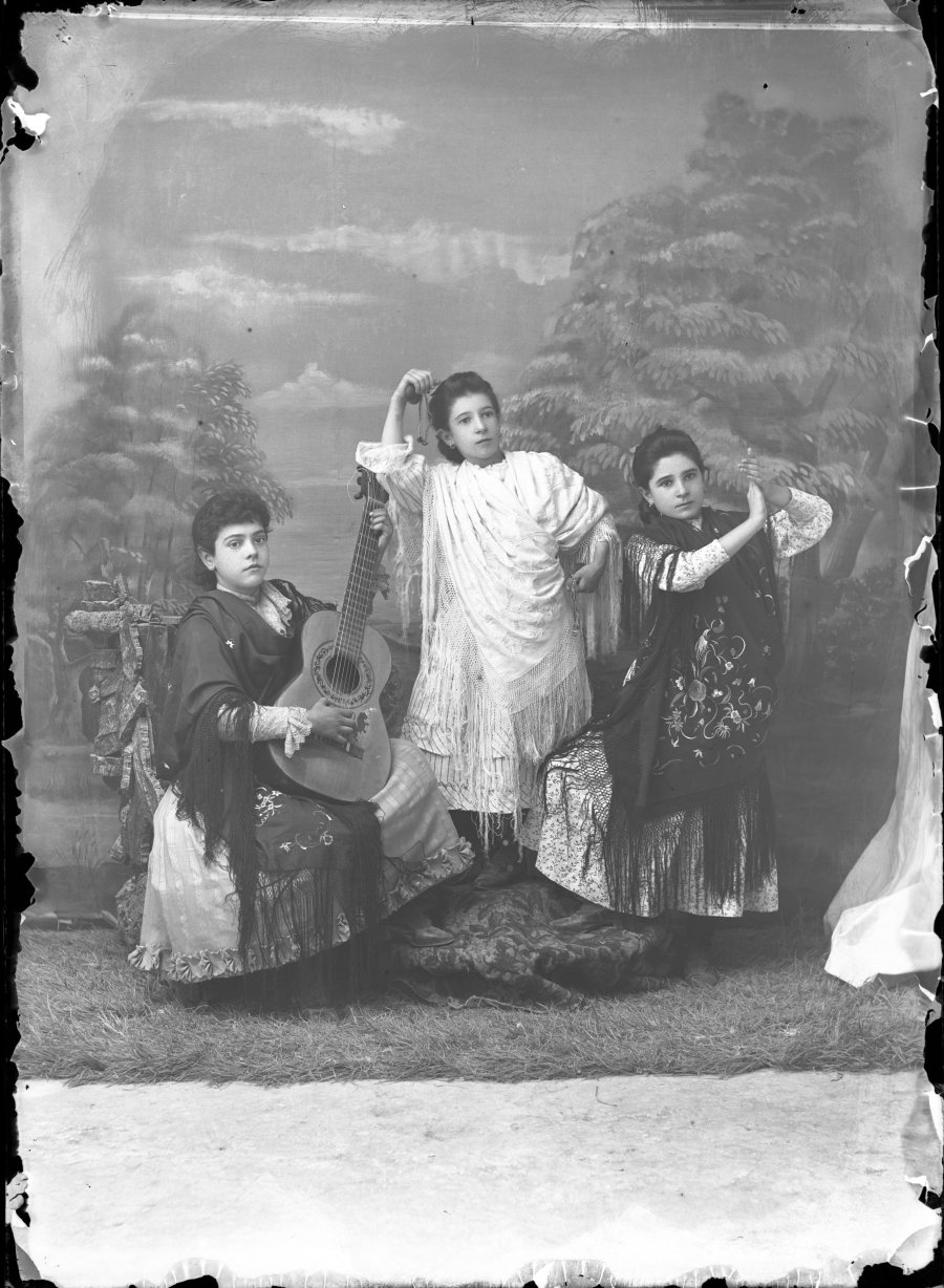 Retrato de estudio de tres niñas representando una escena de baile folclórico