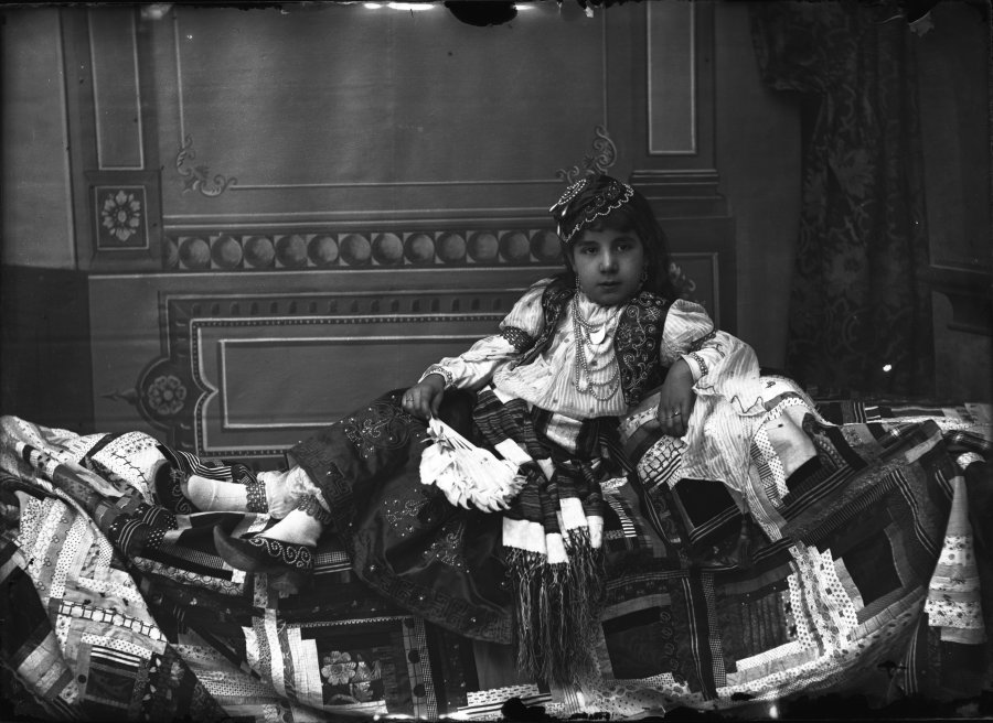 Retrato de estudio de una niña disfrazada de zíngara recostada en un diván