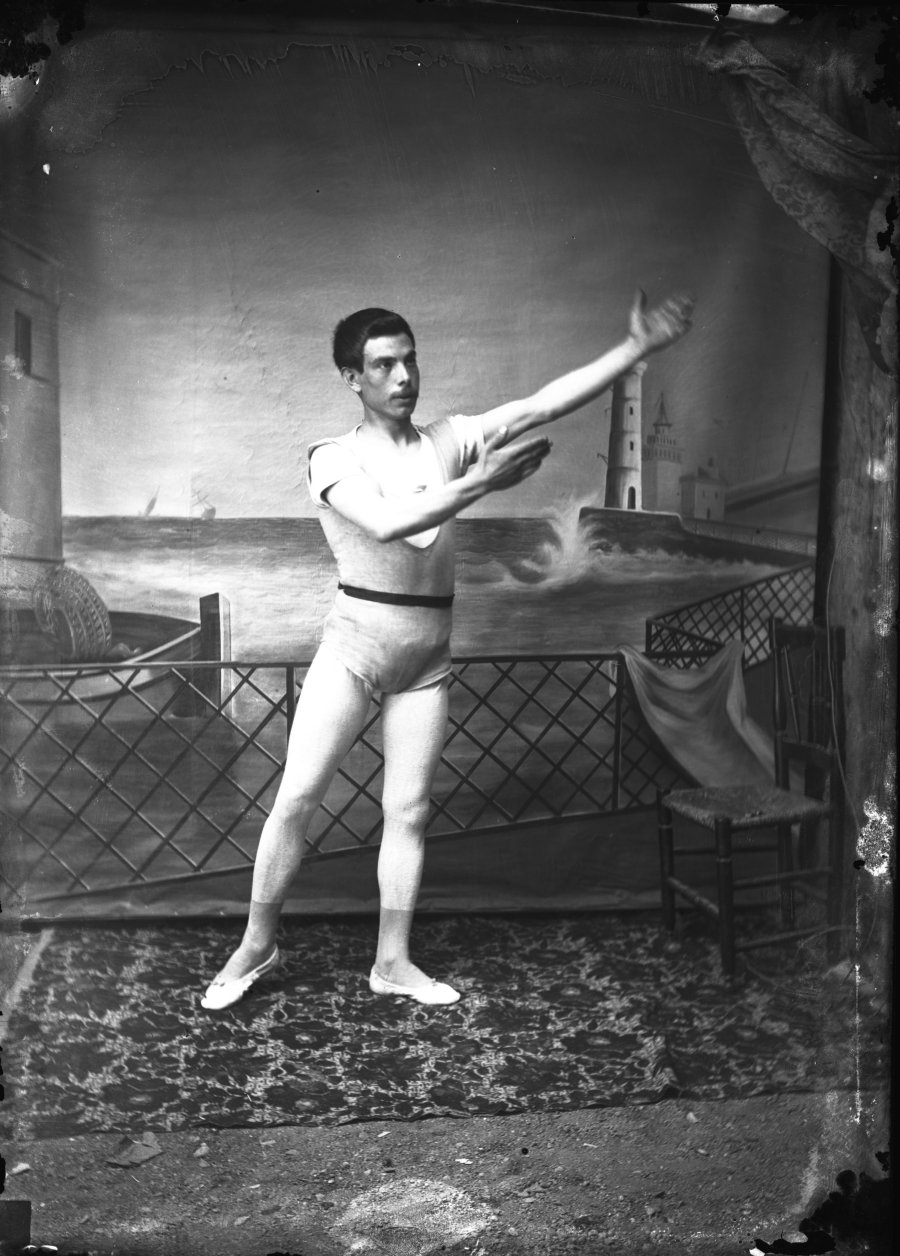 Retrato de estudio de un hombre joven, artista de variedades o de circo, en posición de baile o saludo al público