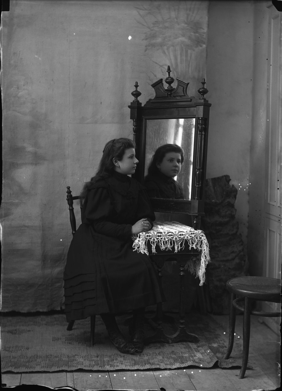 Retrato de estudio de una mujer joven de luto frente a un espejo