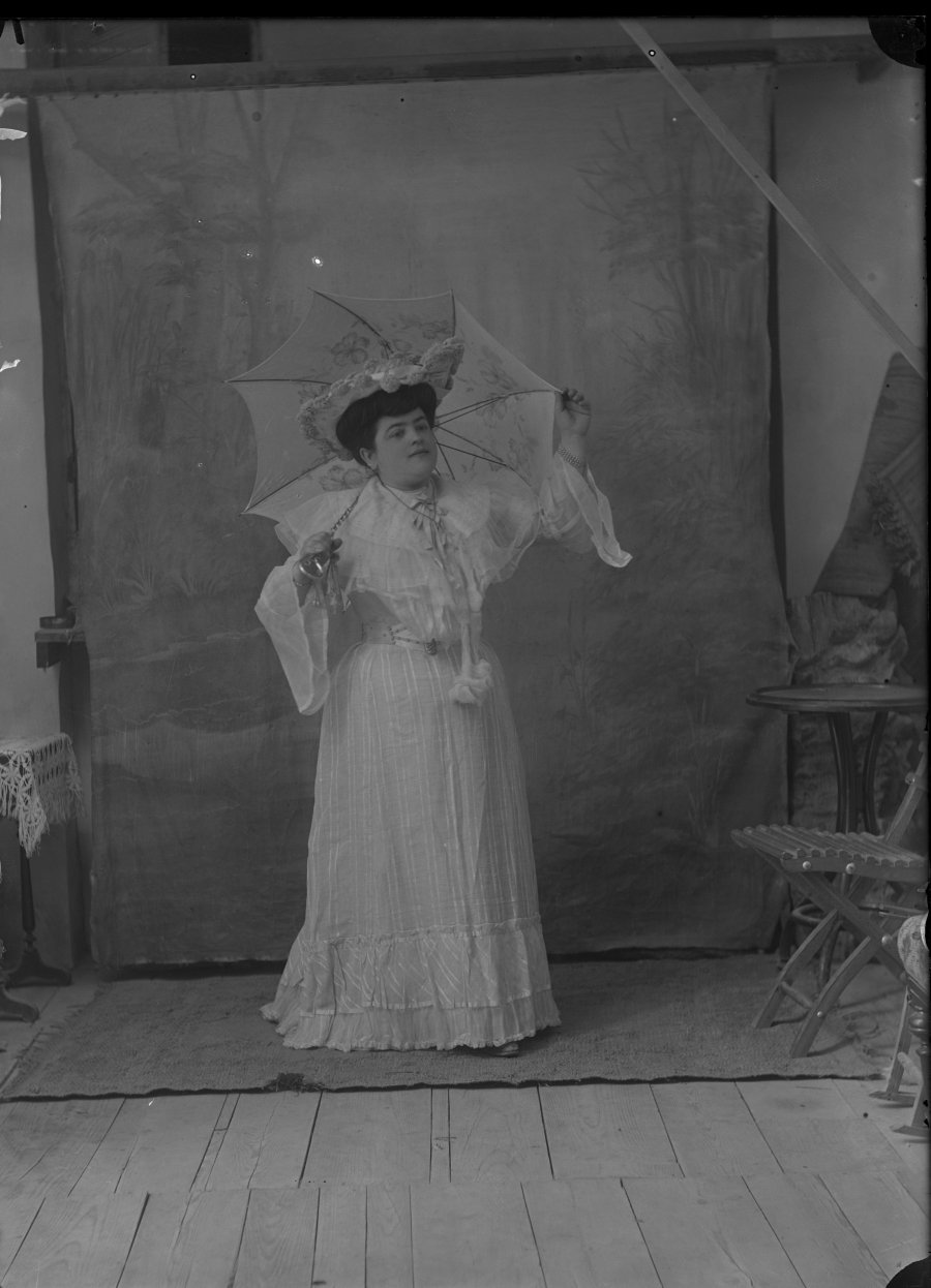 Retrato de estudio de una mujer joven con vestido blanco y sombrilla
