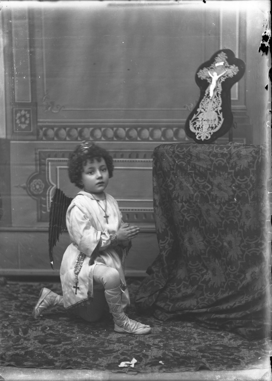 Retrato de estudio de un niño en posición de oración disfrazado de ángel