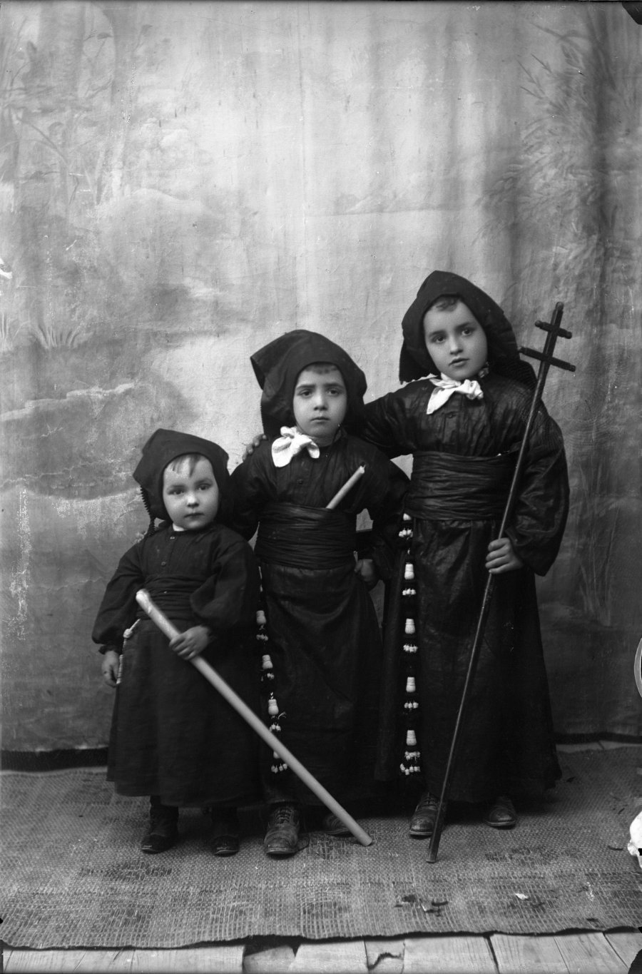Retrato de estudio de tres niños vestidos de nazareno