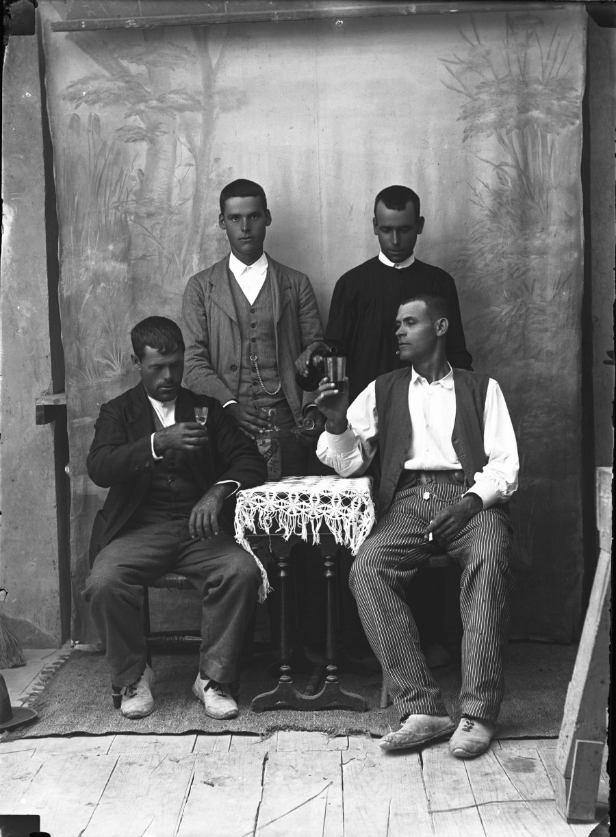Retrato de estudio de cuatro hombres jóvenes bebiendo