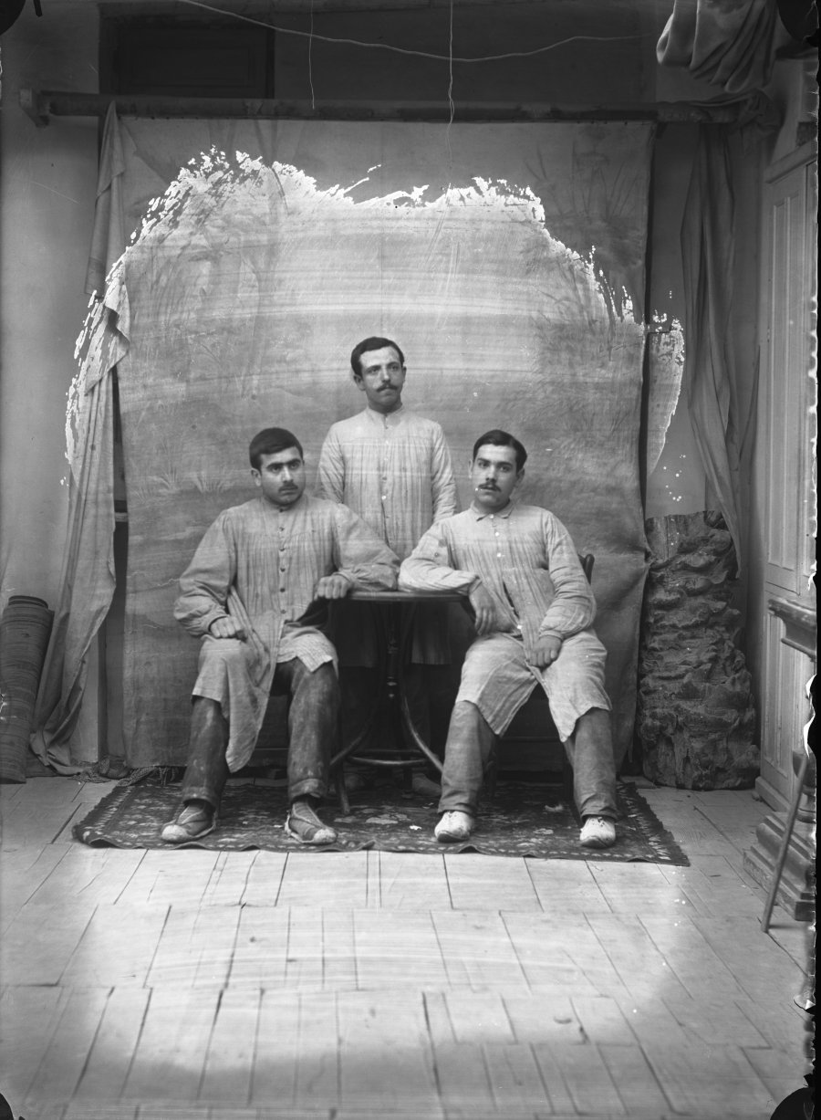 Retrato de estudio de tres hombres jóvenes con uniforme de trabajo