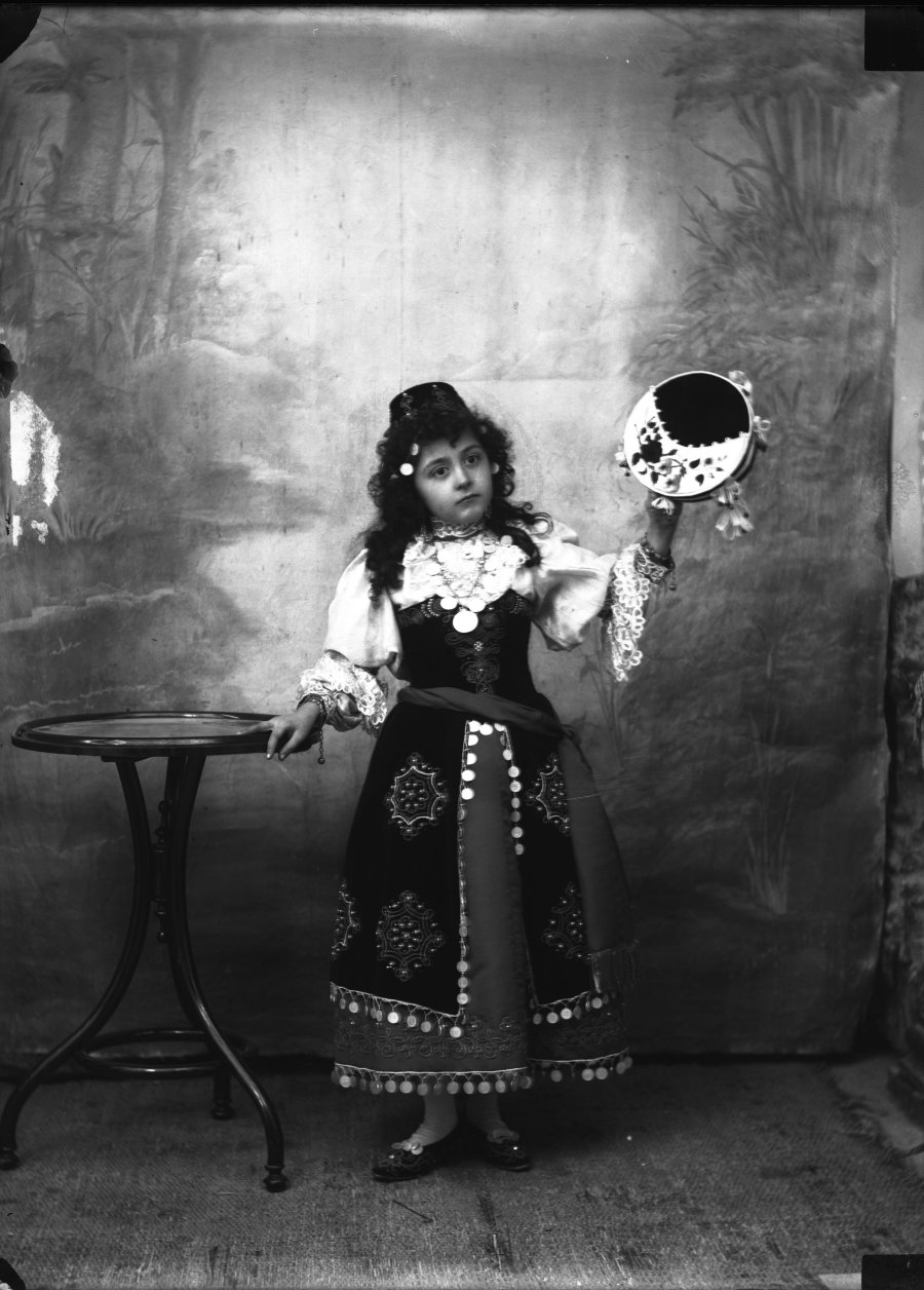 Retrato de estudio de una niña disfrazada de zíngara con pandereta en la mano