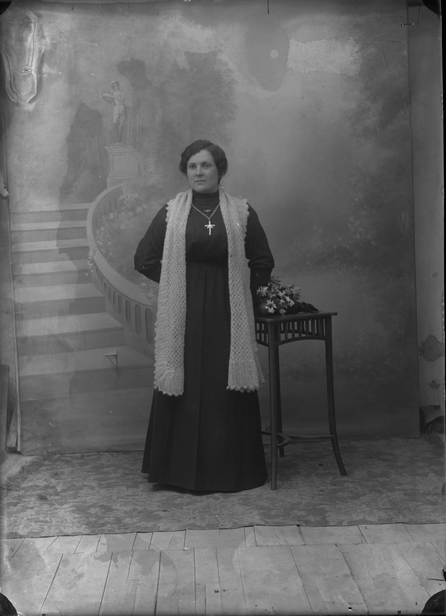 Retrato de estudio de una mujer de luto con bufanda blanca de lana y crucifijo