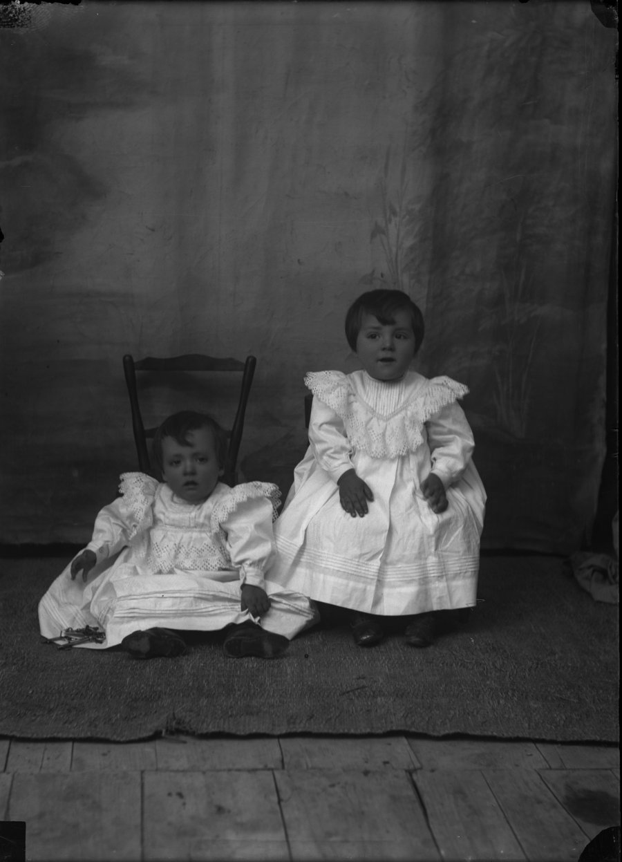 Retrato de estudio de dos niños de pocos meses con vestido blanco