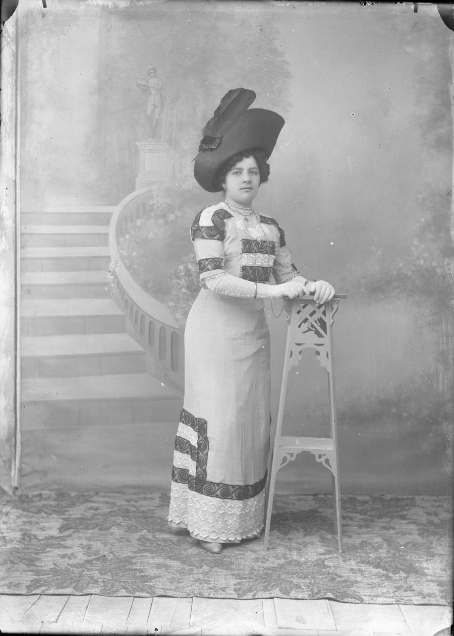 Retrato de estudio de una mujer joven con vestido decorado con espirales y sombrero