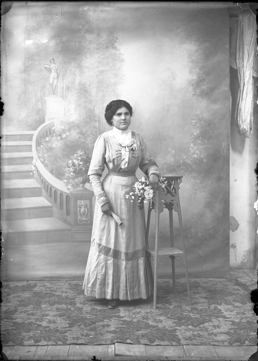 Retrato de estudio de una mujer joven con ramo de flores y abanico