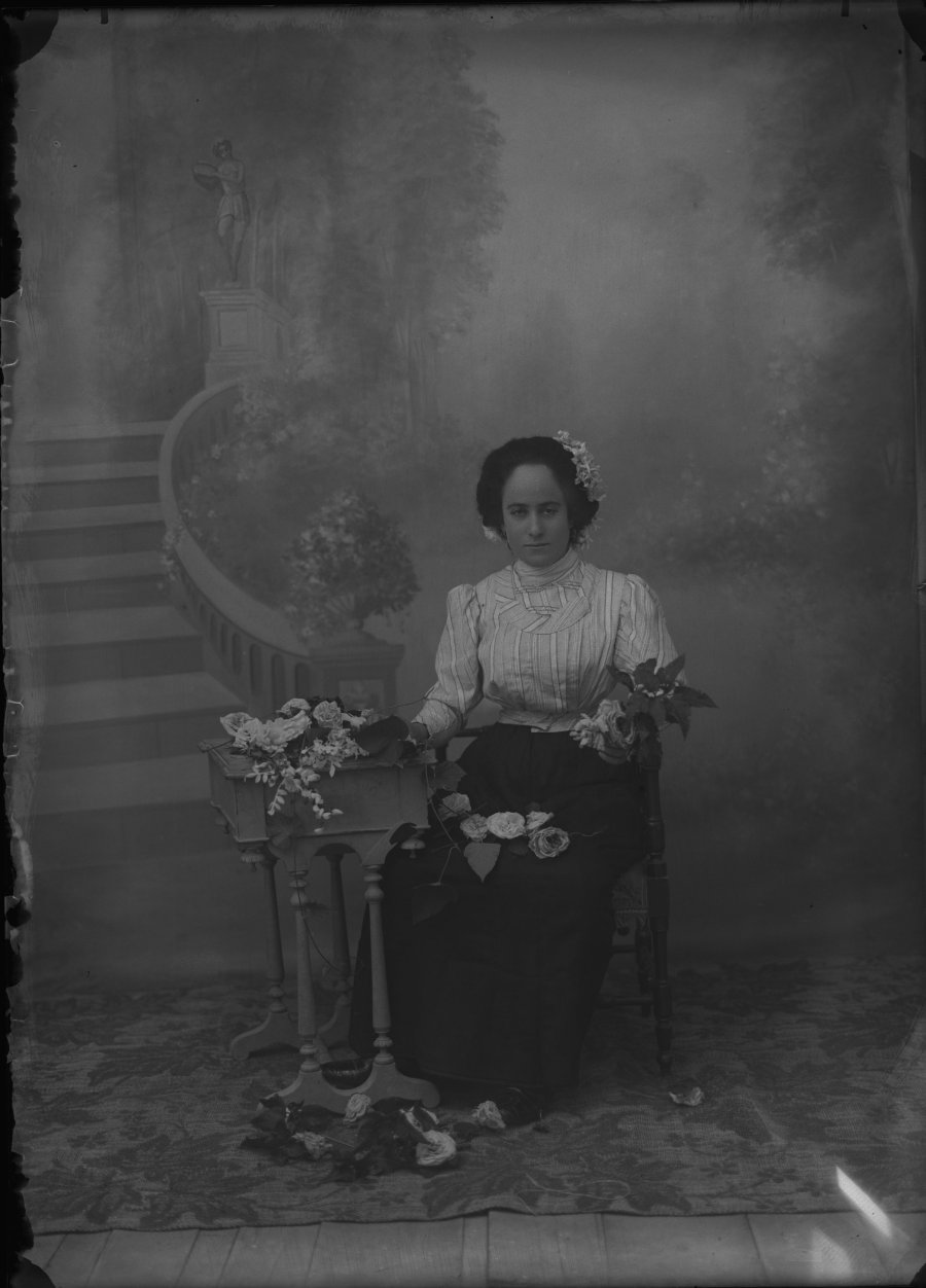 Retrato de estudio de una mujer joven sentada junto a una mesa con flores