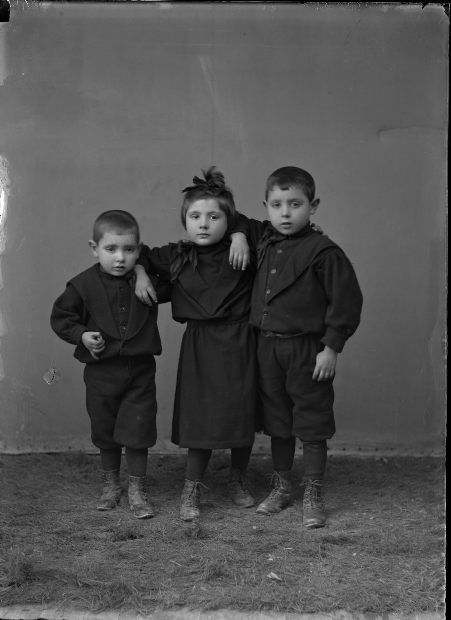 Retrato de estudio de dos niños y una niña vestidos de negro