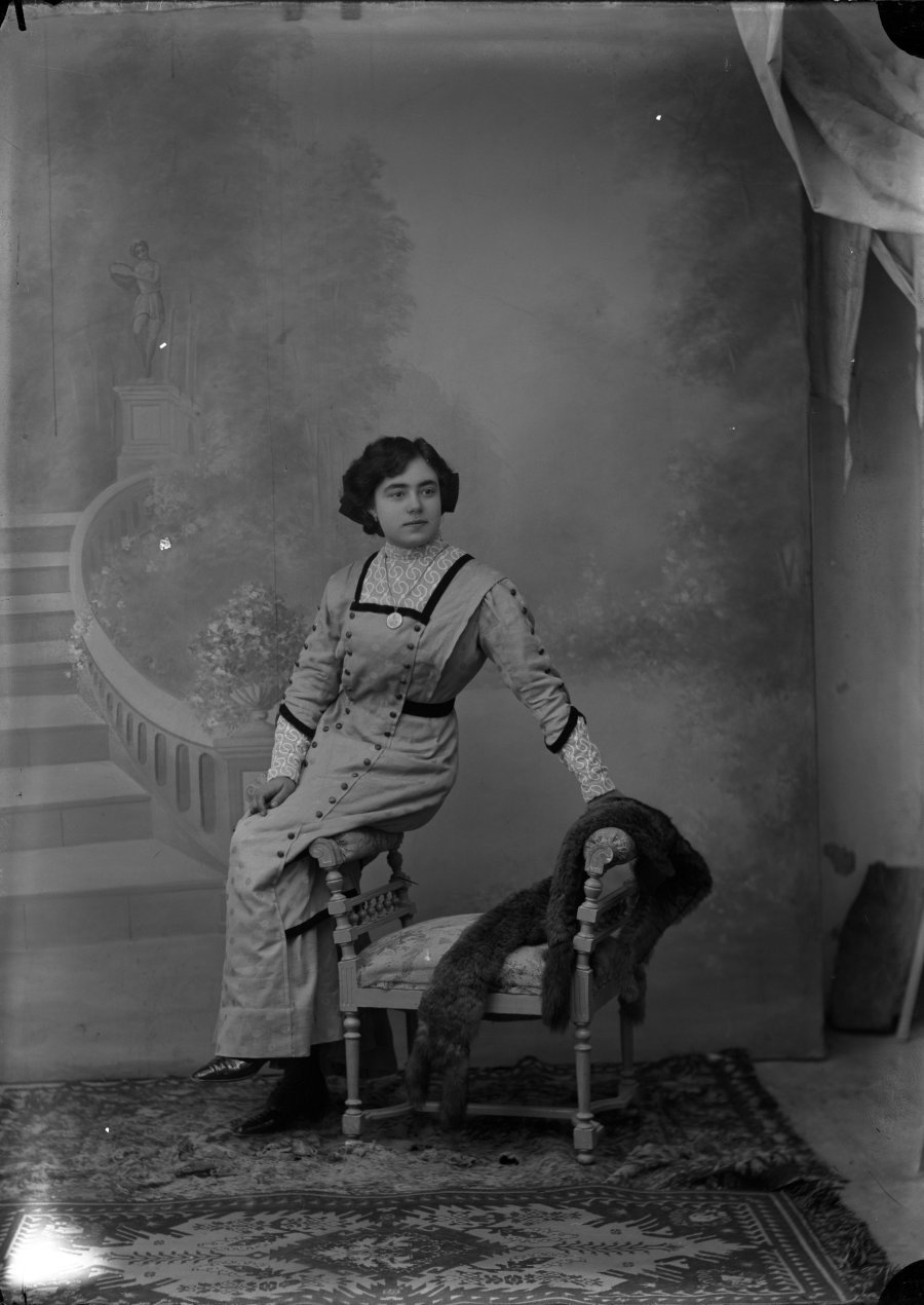 Retrato de estudio de una mujer joven apoyada en un diván pequeño con estola de piel