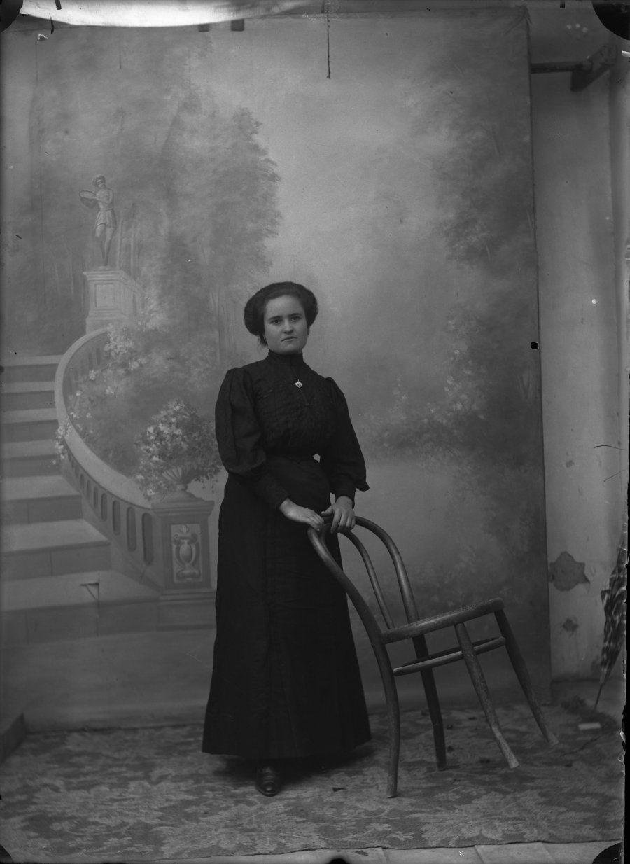 Retrato de estudio de una mujer joven vestida de negro con silla