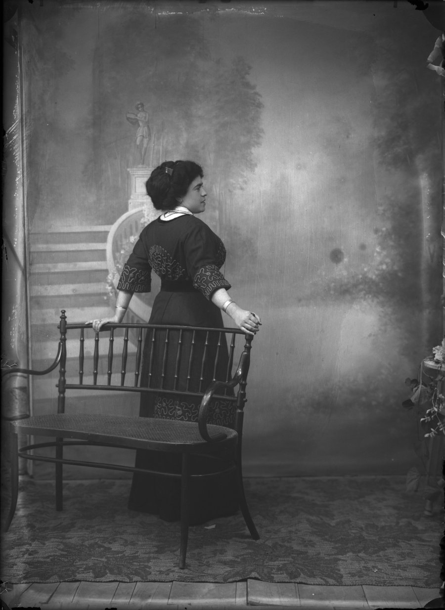 Retrato de estudio de una mujer joven de espaldas junto a un banco de madera