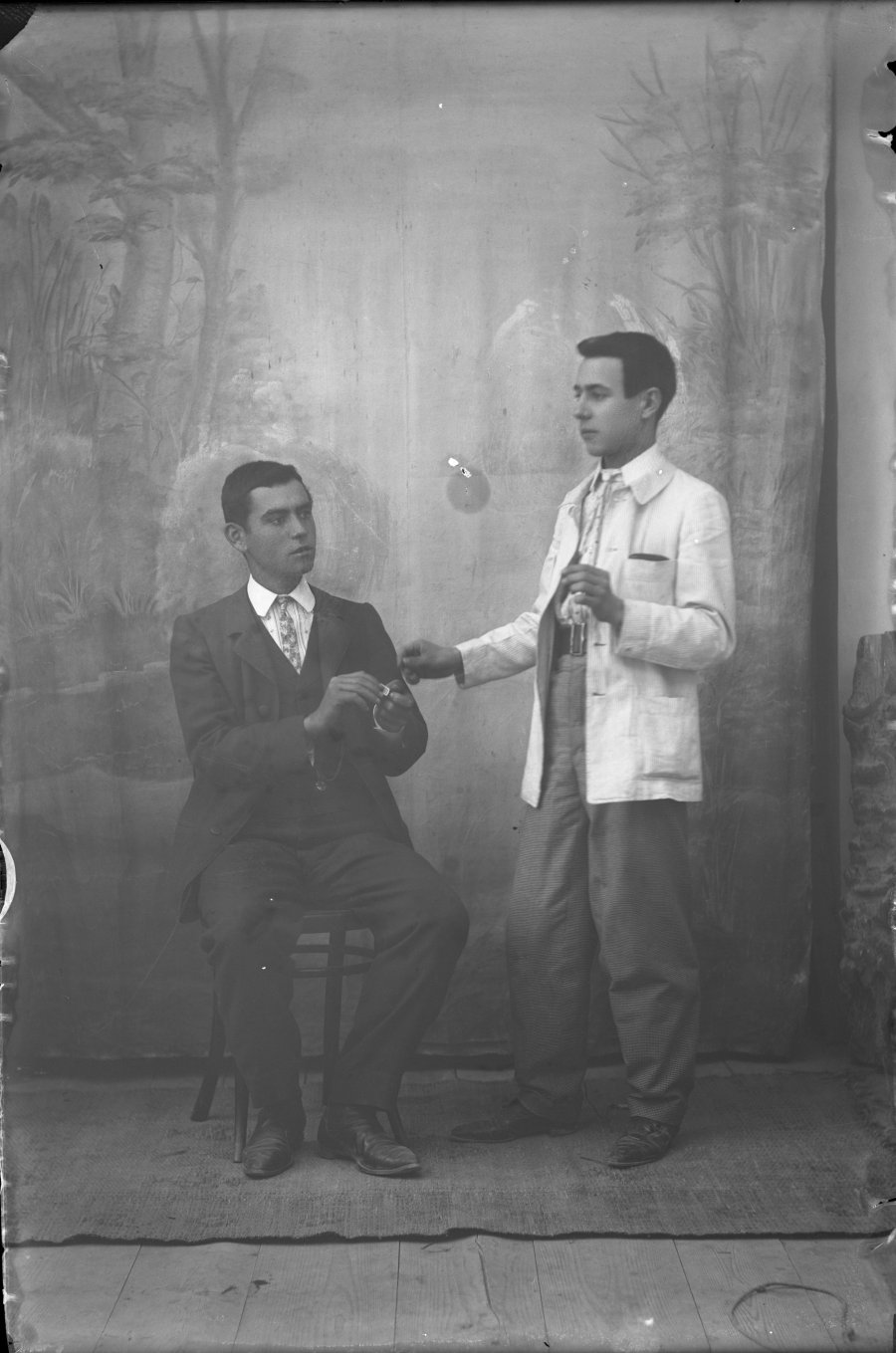 Retrato de estudio de dos hombres jóvenes simulando encender un puro
