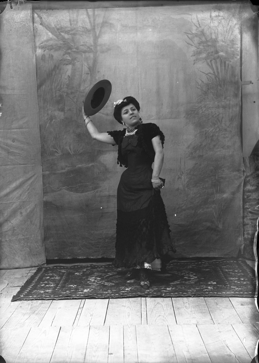Retrato de estudio de una mujer simulando pose de baile con sombrero