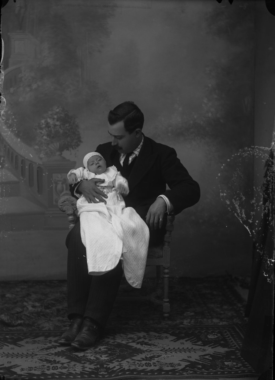 Retrato de estudio de un hombre sentado con un bebé en el regazo