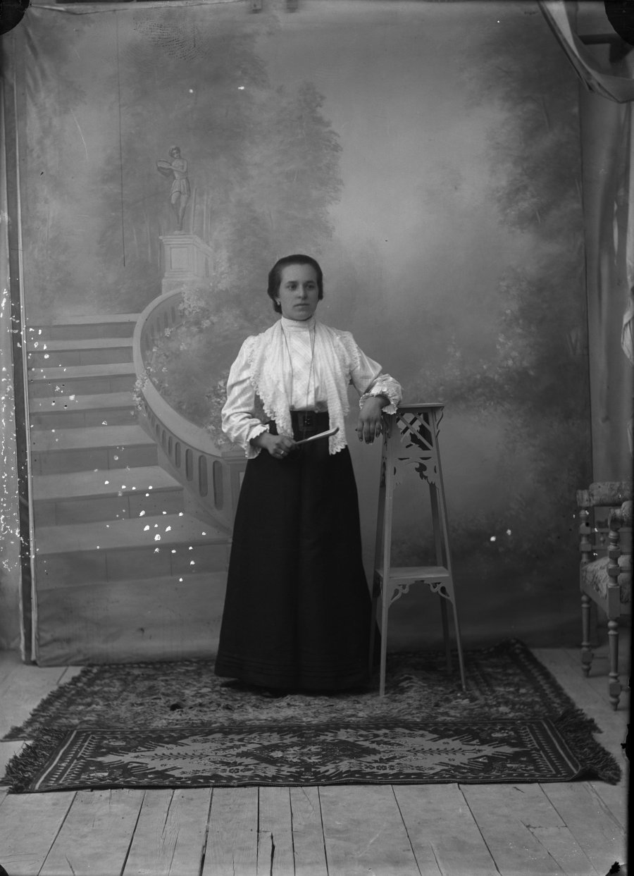 Retrato de estudio de una mujer joven con chal y blusa blanca y falda oscura