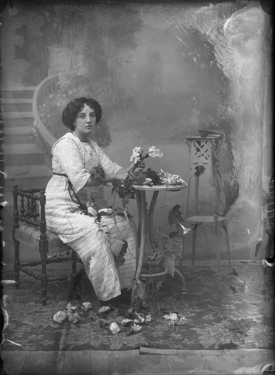Retrato de estudio de una mujer joven sentada simulando formar un ramo de flores