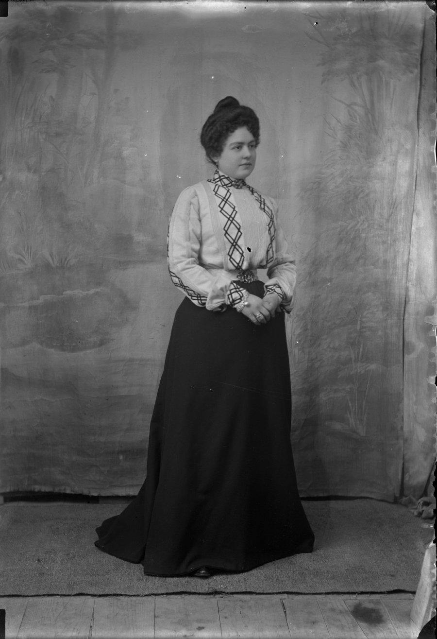 Retrato de estudio de una  mujerjoven con falda negra y blusa con decoración de formas geométricas