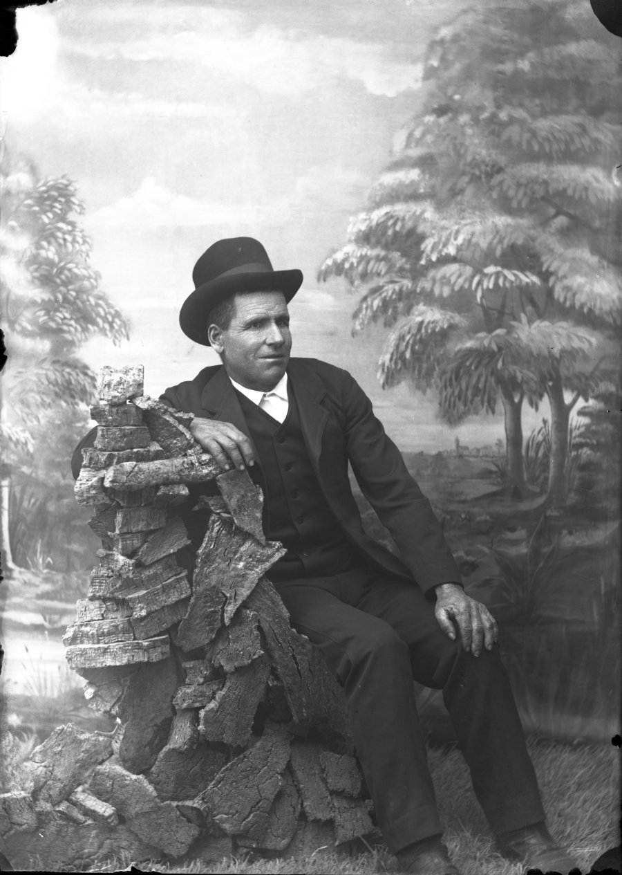 Retrato de estudio de un hombre sentado con traje de tres piezas y sombrero