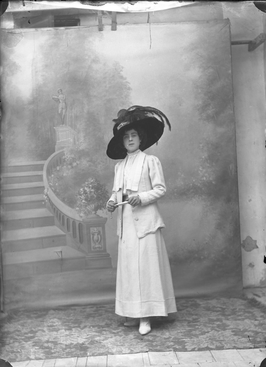 Retrato de estudio de una mujer con vestido blanco y pamela negra