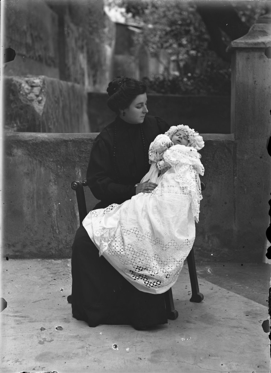 Retrato en exterior de una mujer joven sentada con bebé en el regazo