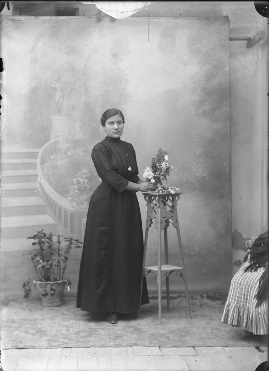 Retrato de estudio de una mujer joven con vestido negro y ramo de flores