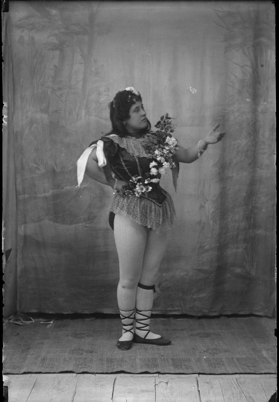 Retrato de estudio de una bailarina con corona de flores a modo de bandolera