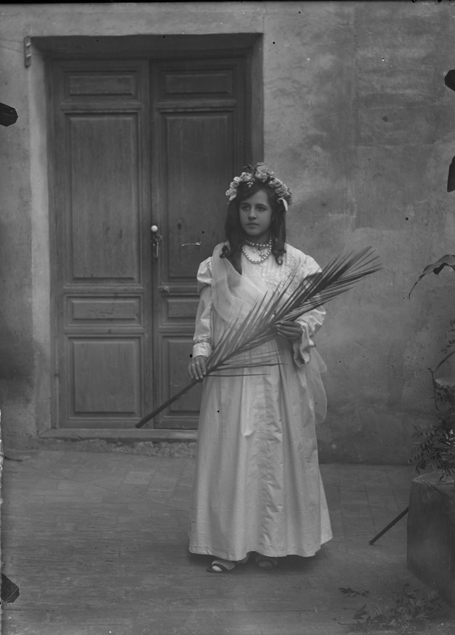 Retrato en exterior de niña ataviada de primera comunión con palma para la procesión del Corpus Christi