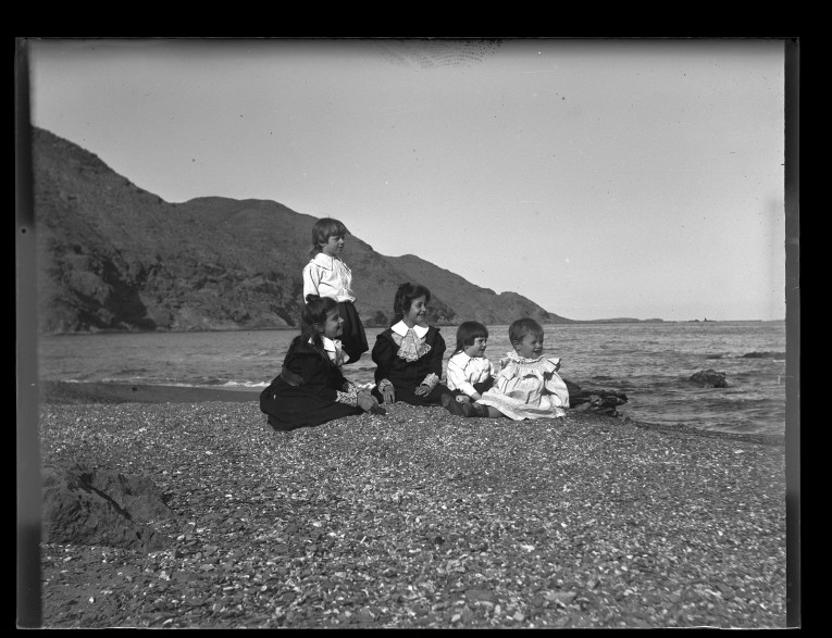 Hijos de Gustavo Gillman sentados junto a la orilla en la playa del Hornillo.
