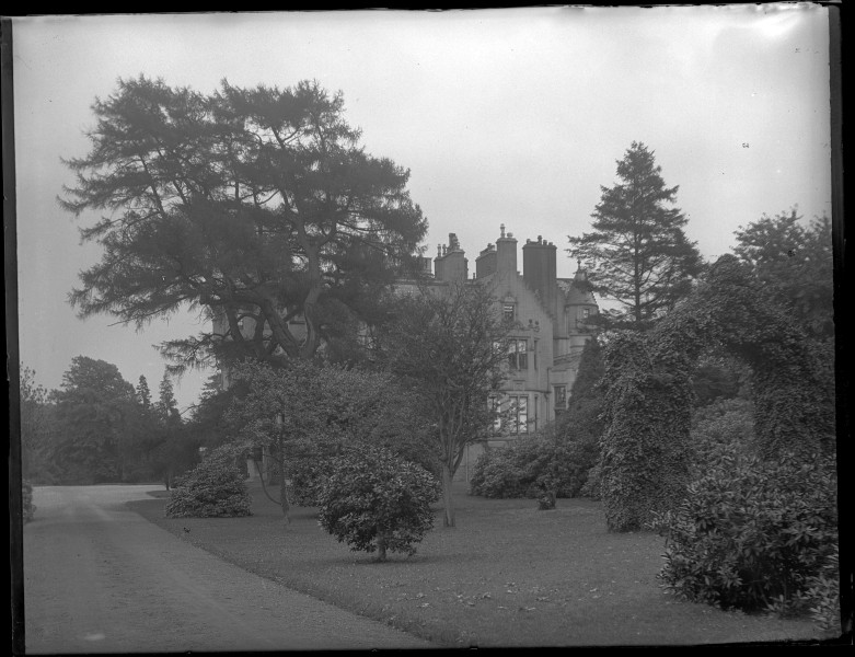 Vista parcial de la fachada lateral de la casa Craigends en Renfrewshire (Escocia) semioculta entre los árboles.